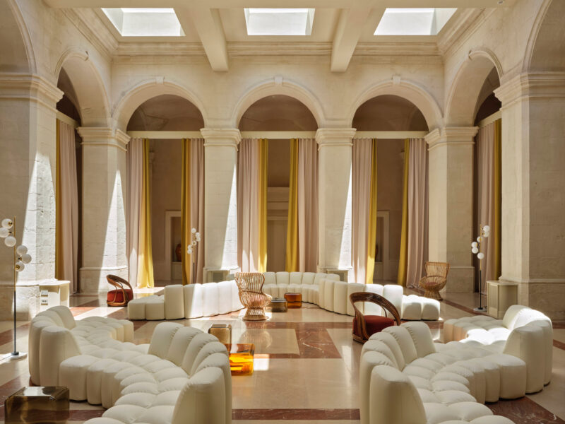 Modern lounge area in Villa Ostuni featuring curved white seating, warm lighting, and elegant architectural arches.