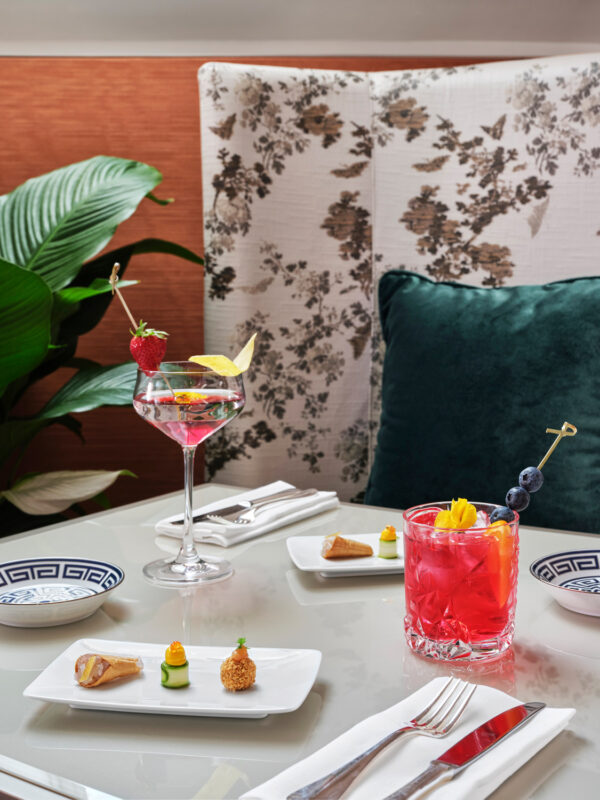 Elegant table setting featuring a cocktail and a mocktail, with gourmet appetizers, in a stylish restaurant interior.