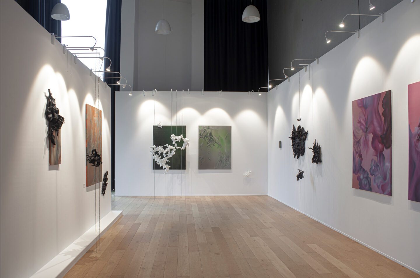 Art gallery interior featuring various artworks on white walls, with sculptures and paintings illuminated by soft lighting.