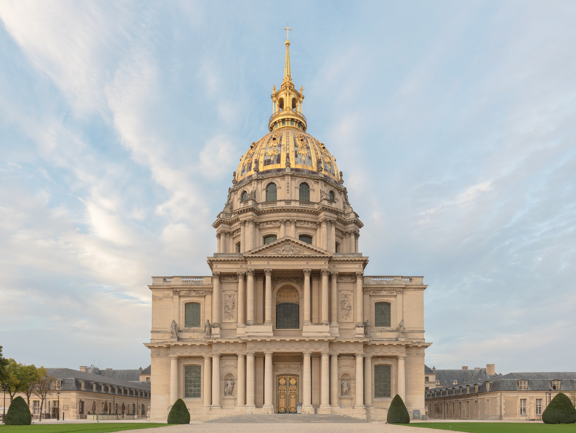 Dome of Les Invalides in Paris, featuring a golden spire against a cloudy sky.
