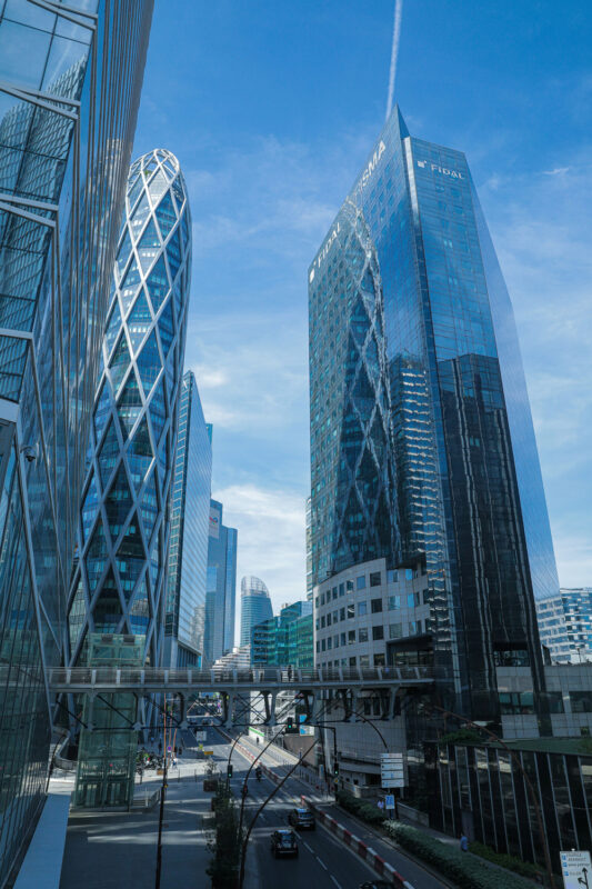 Modern skyscrapers in La Défense, Paris, featuring glass facades and unique architectural designs under a clear blue sky.