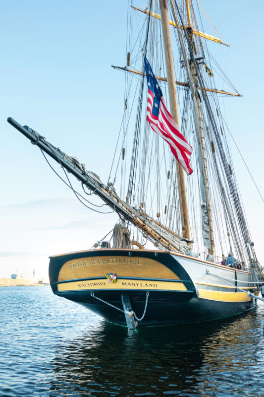 Sailing ship "Pride of Baltimore II" docked in water with the American flag flying.