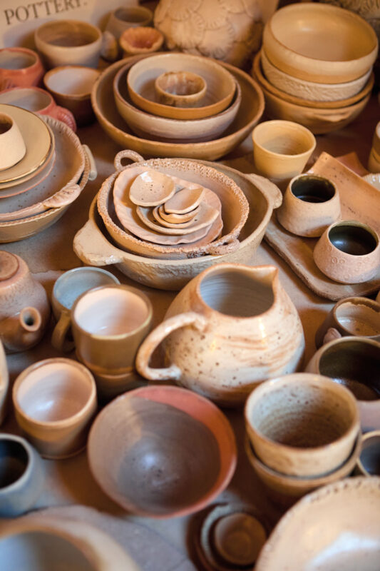 A variety of handcrafted pottery, including bowls, cups, and a pitcher, arranged on a table.