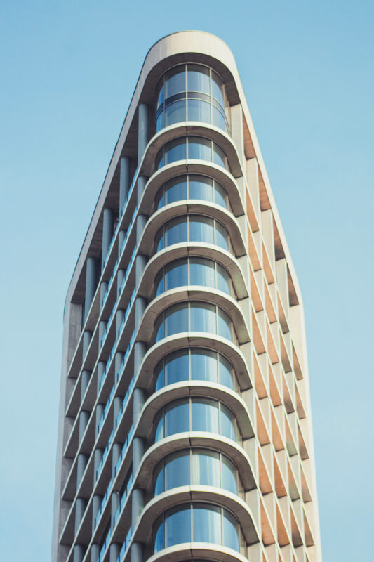 Modern building with a curved facade and large windows, set against a clear blue sky.