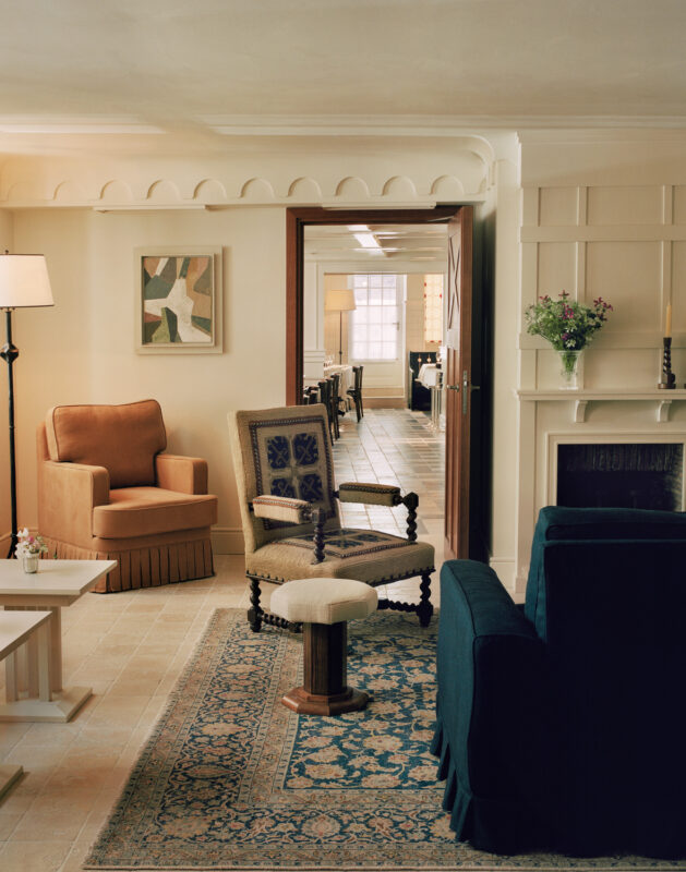 Elegant interior of Château Voltaire featuring a cozy seating area with a blue sofa, armchairs, and decorative rug.