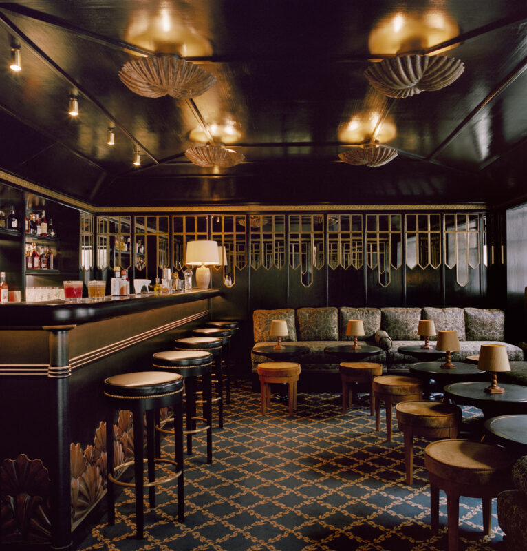 Elegant bar interior with dark wood paneling, plush seating, and decorative lighting, showcasing a sophisticated atmosphere.