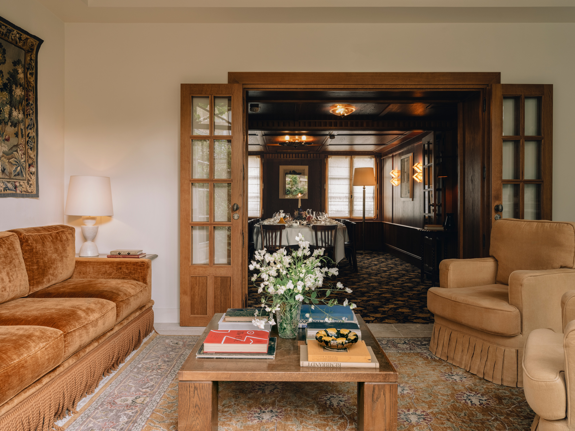 Cozy interior of Château Voltaire featuring a living room with a brown sofa, coffee table, and a view into a dining area.
