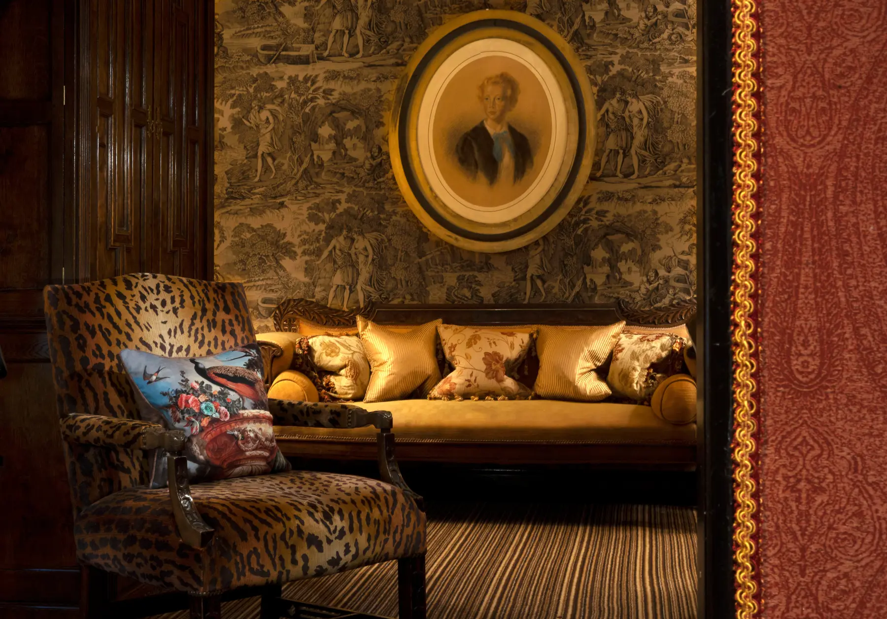 Elegant sitting area in Prestonfield House featuring a leopard-print chair, a gold sofa, and vintage wallpaper with a port...