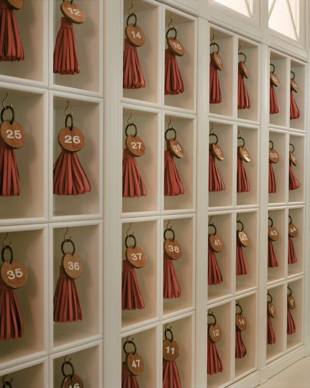 Wall display of numbered key fobs in red and brown, arranged in a grid pattern at Château Voltaire.