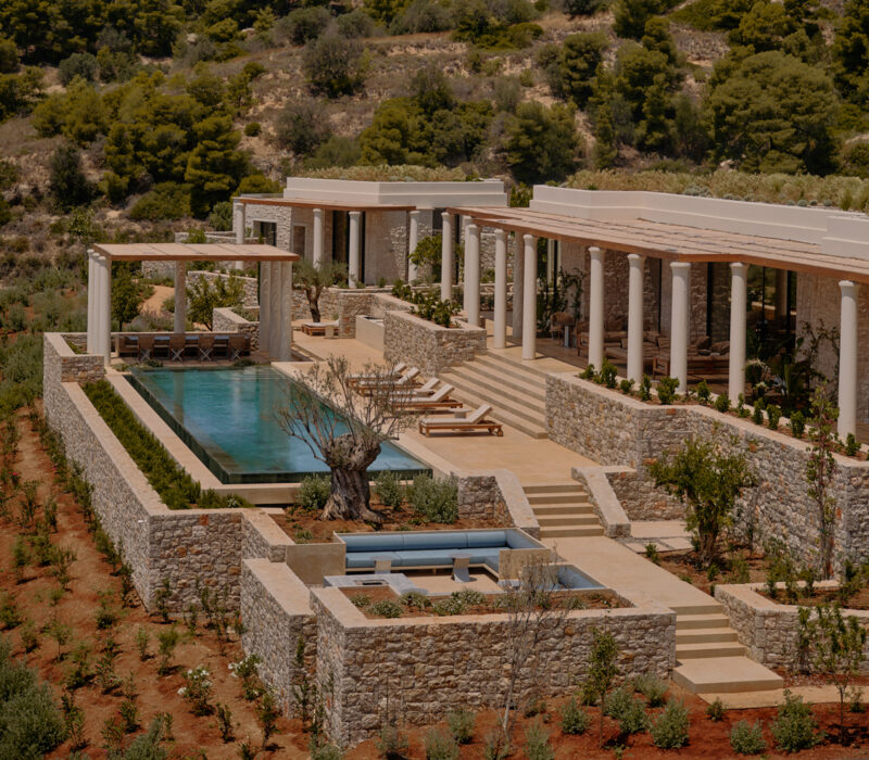 Modern villa with a pool, surrounded by landscaped gardens and hills in Amanzoe, Greece.