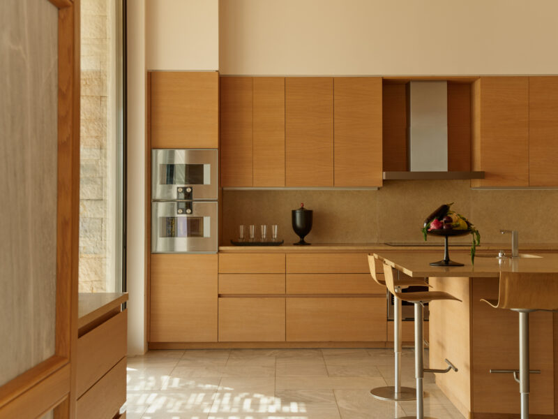 Modern kitchen in Villa 21 at Amanzoe, featuring wooden cabinetry, a central island, and elegant decor.
