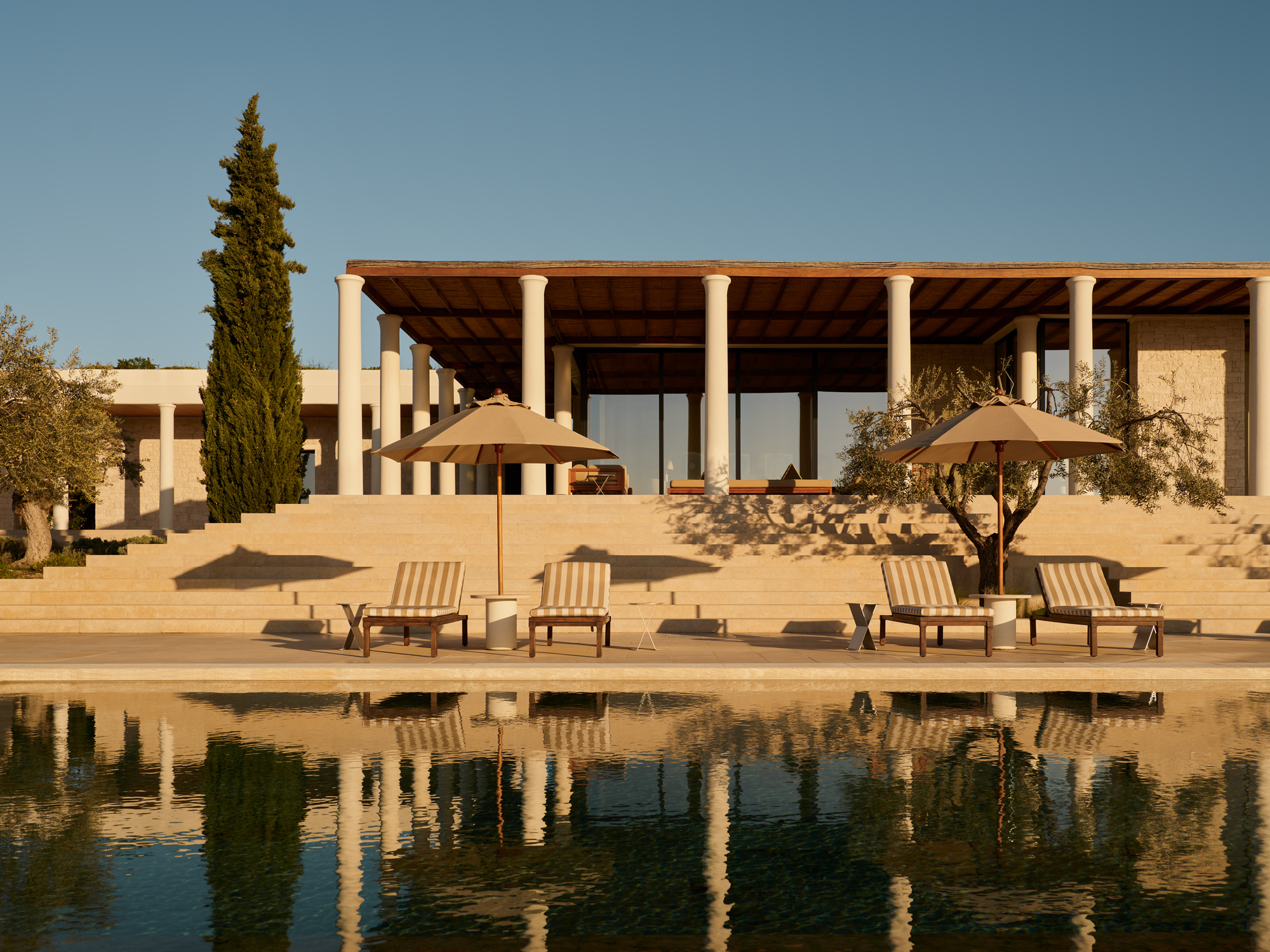 Villa 3 at Amanzoe, Greece, featuring a pool, sun loungers, and a modern architectural design against a clear sky.