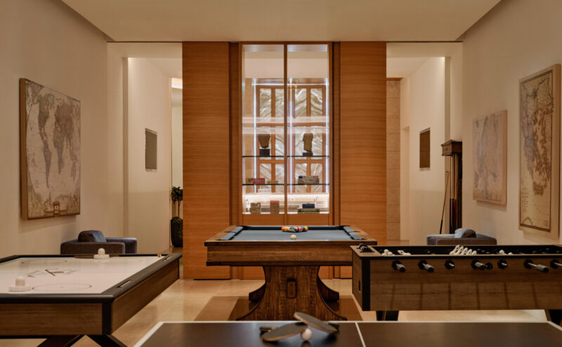 Games room at Amanzoe, featuring a pool table, foosball table, and maps on the walls. Modern and spacious design.