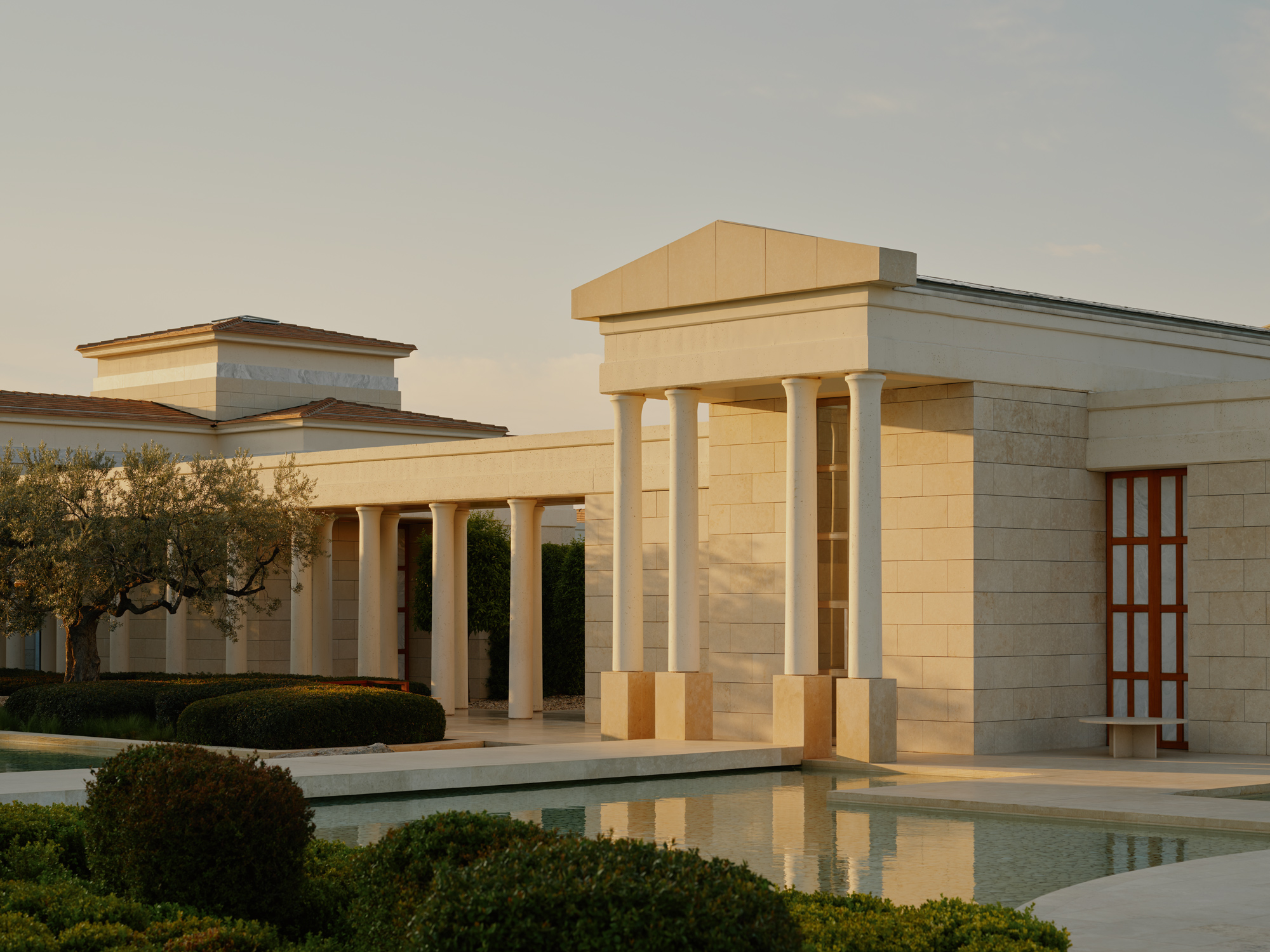 Elegant resort architecture at Amanzoe, Greece, featuring columns, landscaped gardens, and a serene pool.
