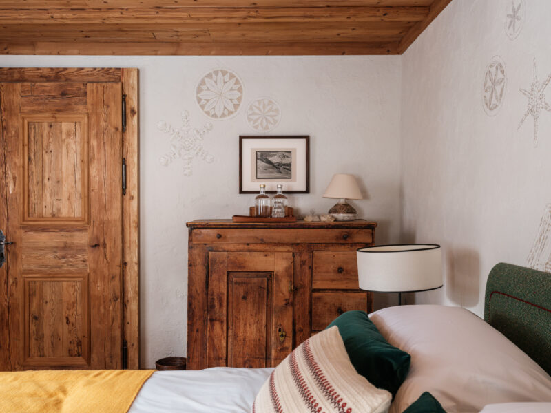 Cozy bedroom featuring a wooden door, vintage dresser, framed artwork, and decorative snowflake wall designs.