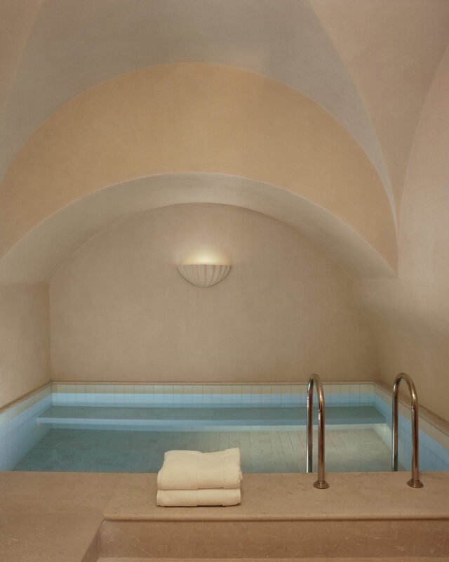 Spa area featuring a cold plunge pool with light blue water, surrounded by smooth beige walls and an arched ceiling.