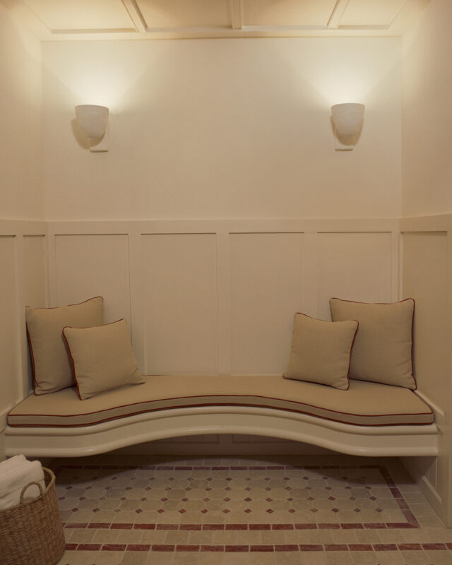 Spa area featuring a curved bench with cushions, soft lighting, and tiled flooring.