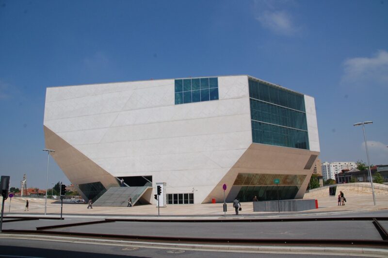 Modern architectural design of Casa da Música, featuring angular white facade and large glass windows under a clear blue ...