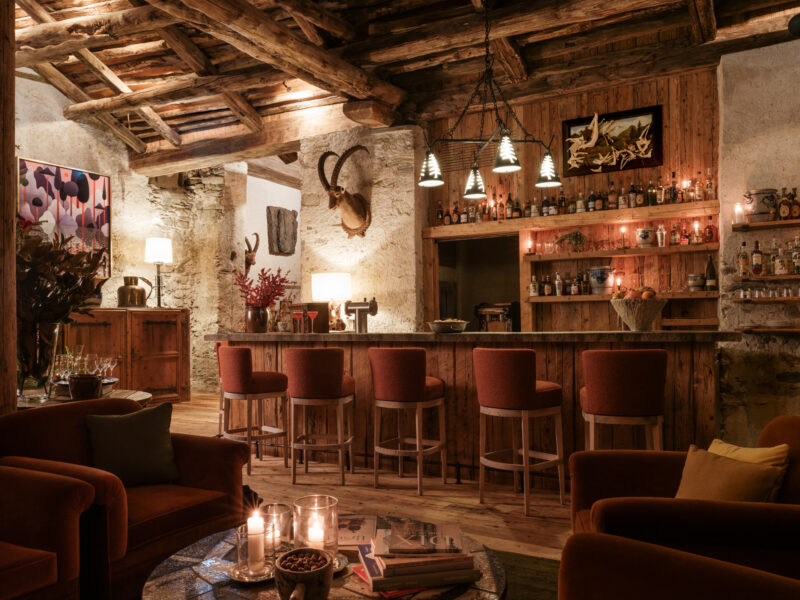 Cozy cocktail bar with wooden decor, featuring a well-stocked bar, plush seating, and warm lighting.