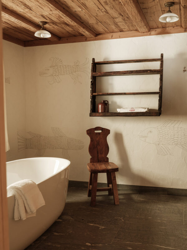 Modern bathroom featuring a freestanding tub, wooden chair, and fish-themed wall decor.