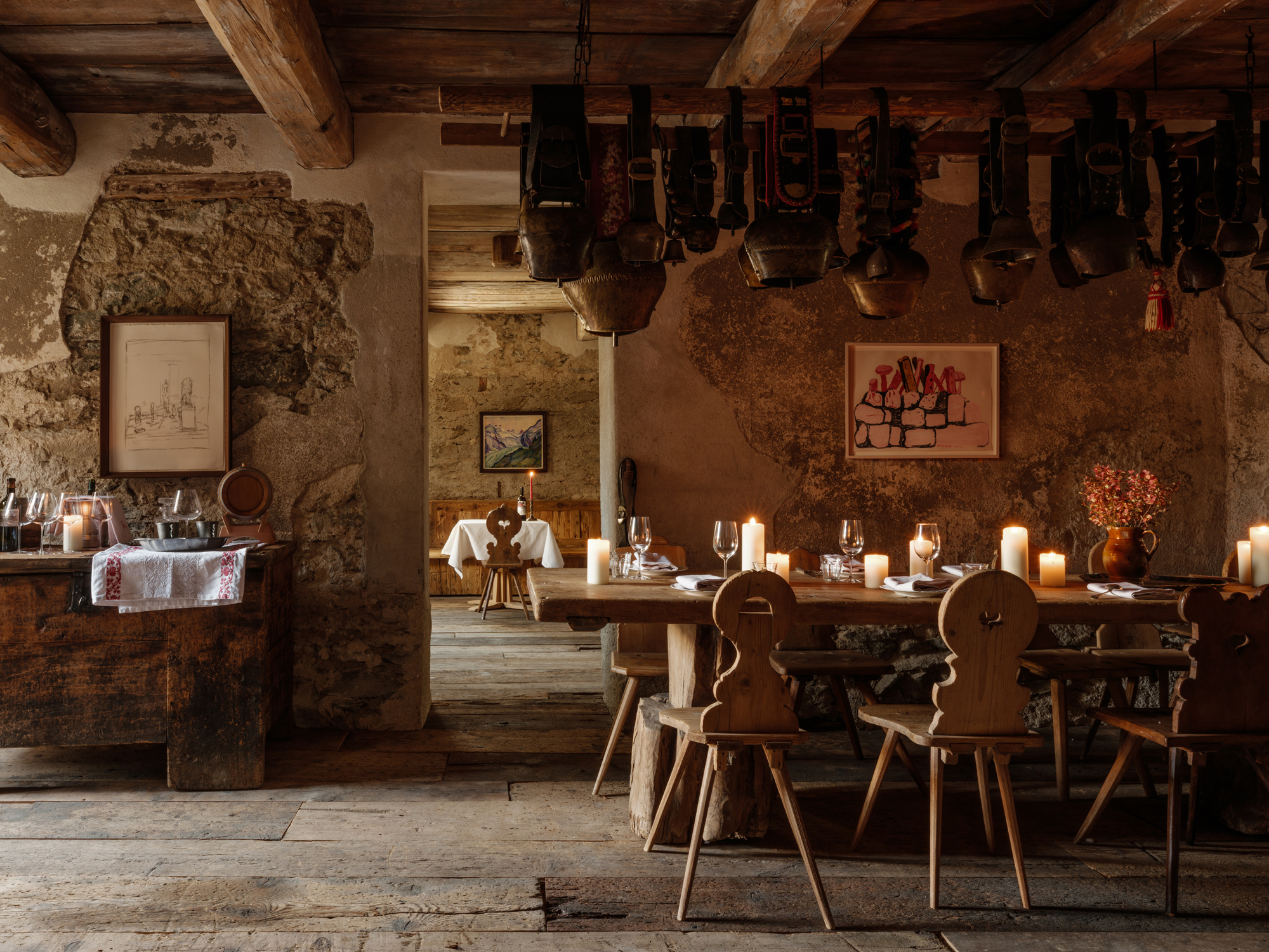 Rustic dining area in Chesa Marchetta, featuring wooden tables, candlelight, and traditional decor.