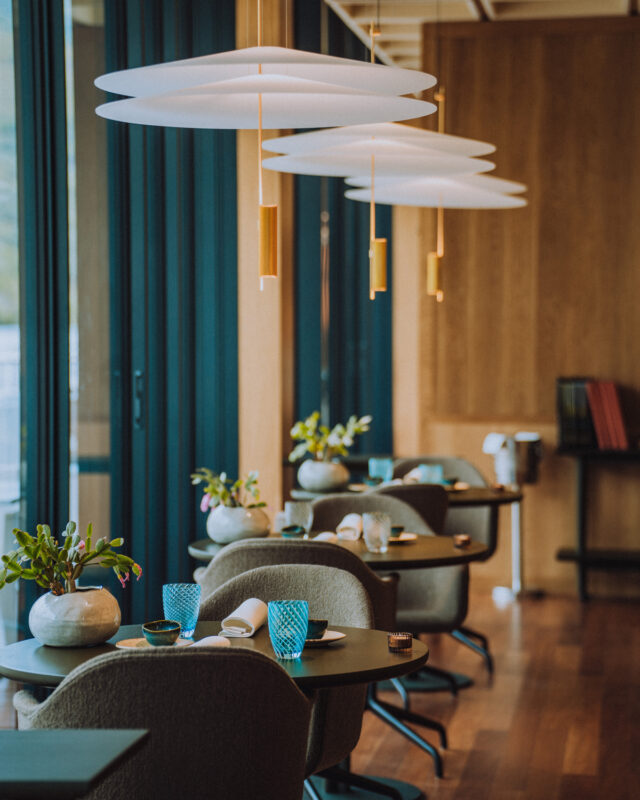 Modern restaurant interior featuring elegant tables, stylish lighting, and decorative plants.
