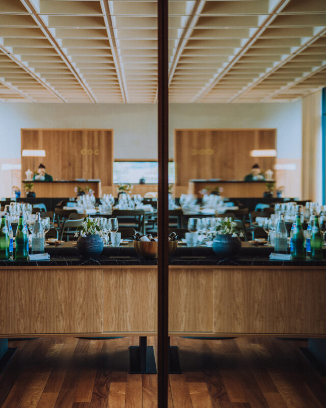 Elegant restaurant interior featuring a mirrored bar, wooden furnishings, and neatly arranged table settings.