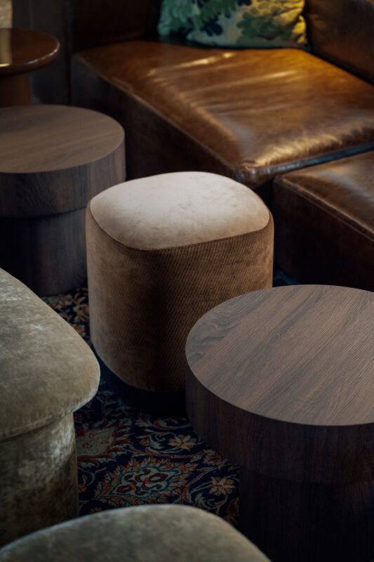 Stylish seating arrangement featuring a brown upholstered ottoman and wooden side tables in a cozy lounge setting.