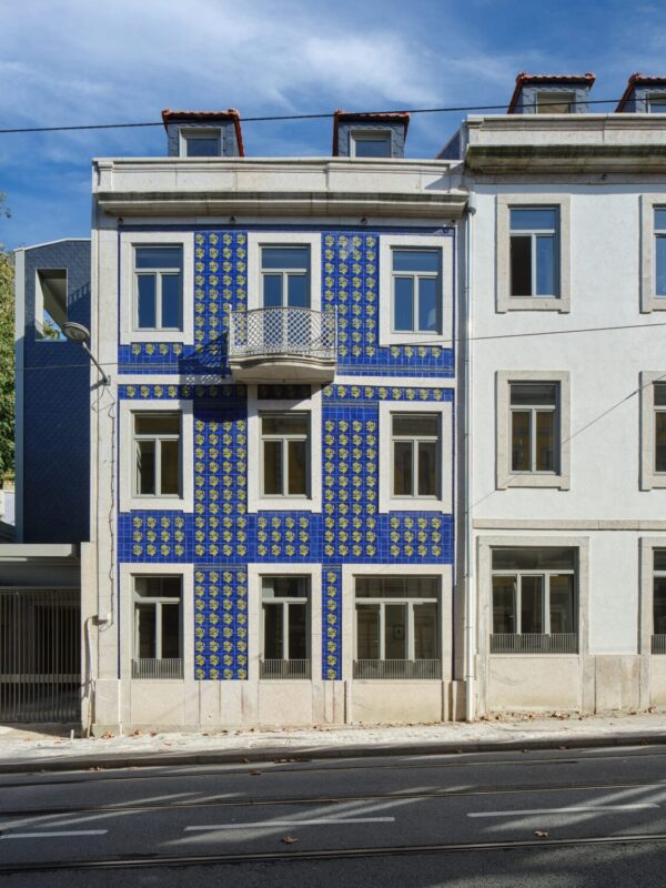Blue-tiled facade of Massarelos House in Porto, Portugal, featuring a balcony and adjacent buildings.