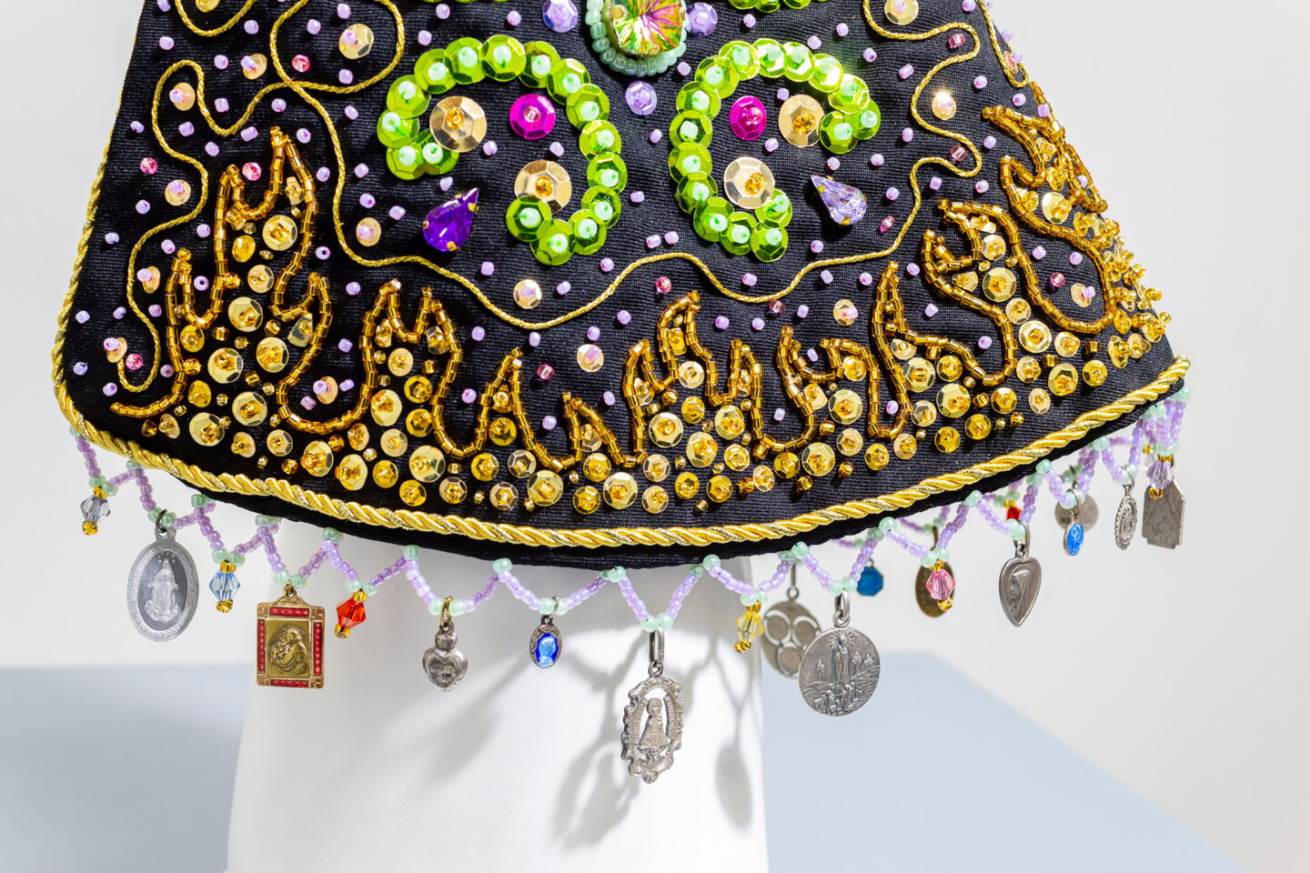Colorful embroidered fabric with sequins and charms hanging from the edge, showcasing intricate designs and textures.