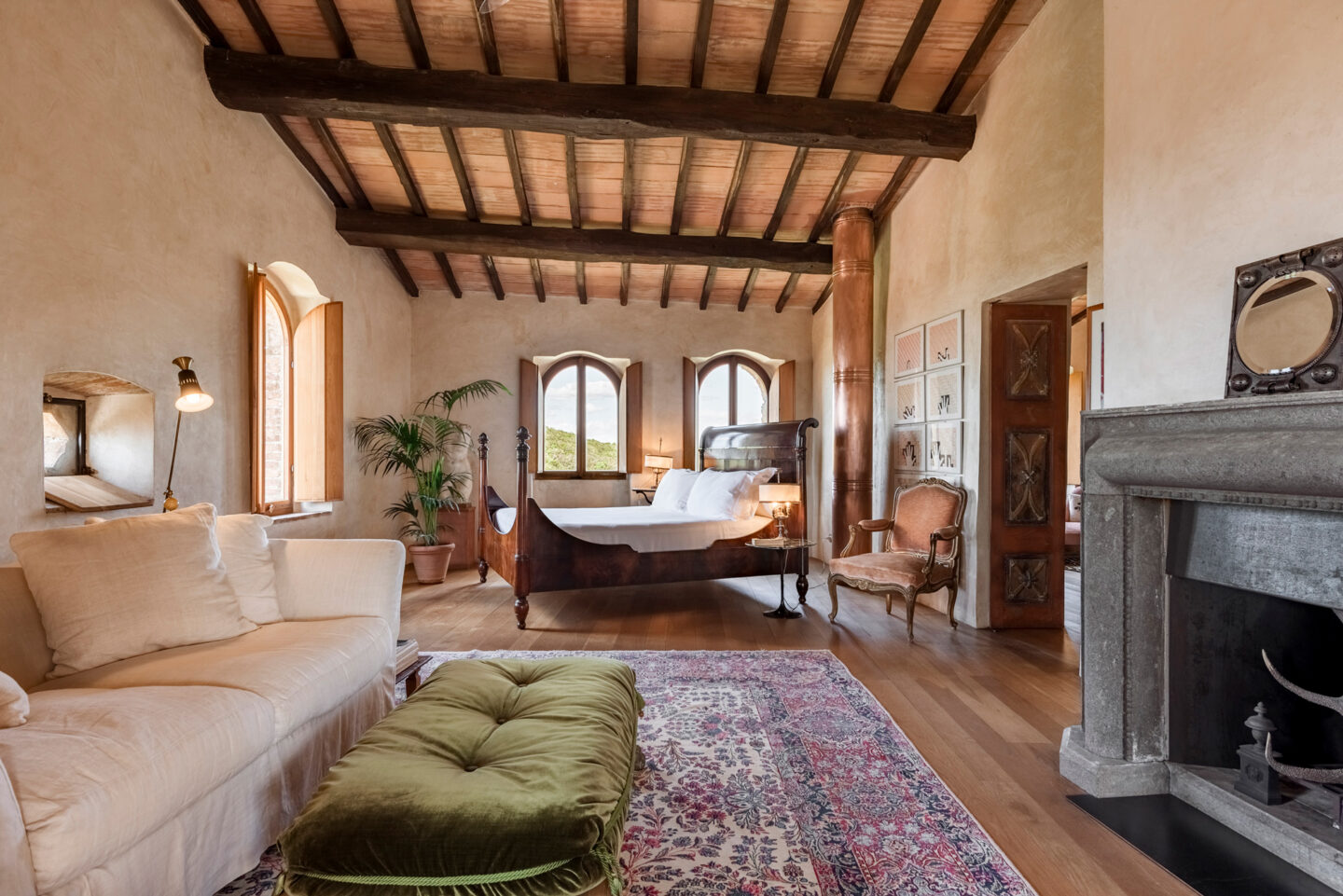 Elegant bedroom in Castello di Vicarello featuring a wooden bed, cozy seating area, and rustic decor.