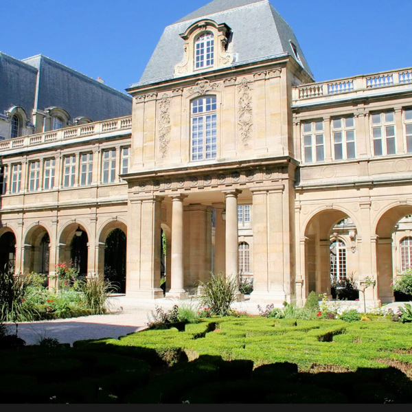 Historic building with ornate architecture and a garden, located in the Musée Carnavalet, Paris.