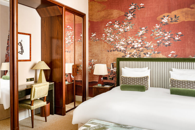 Elegant junior suite at Saint James Paris featuring a floral wallpaper, a king-size bed, and a stylish desk area.