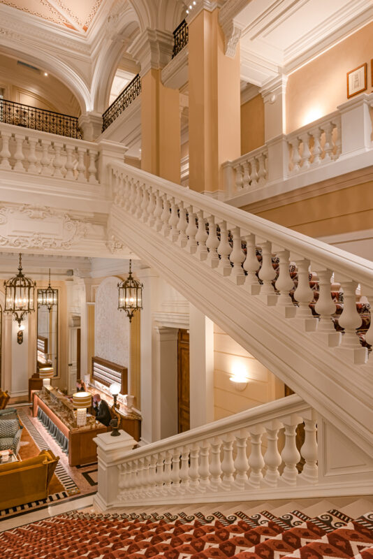 Elegant lobby of Saint James Paris featuring a grand staircase, ornate chandeliers, and a reception area.