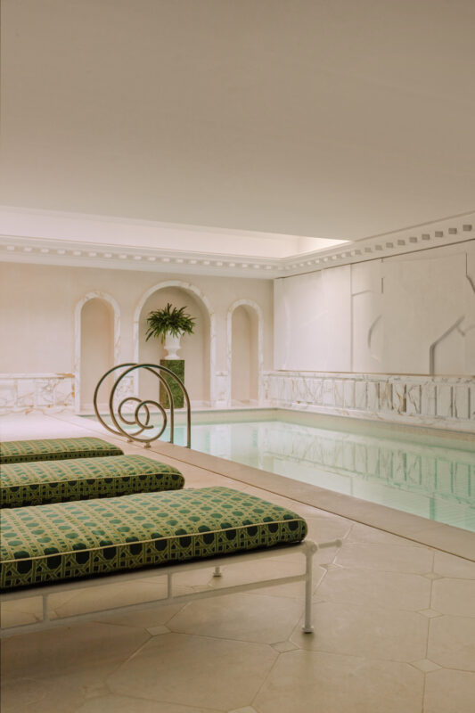 Wellness area at Saint James Paris featuring a pool, green patterned loungers, and elegant marble accents.
