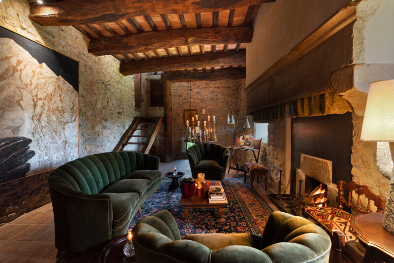 Cozy living room in Castello di Vicarello with green sofas, a fireplace, and rustic decor.