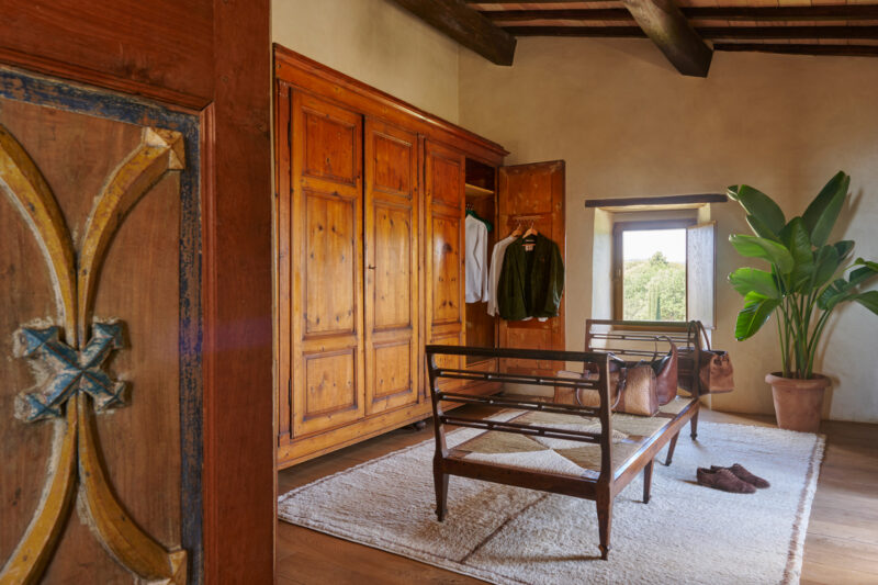 Cozy room with wooden wardrobe, a bench, and a plant, featuring a window with a view of the outdoors.