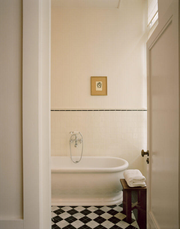 Elegant bathroom featuring a freestanding tub, black and white tiled floor, and a framed artwork on the wall.