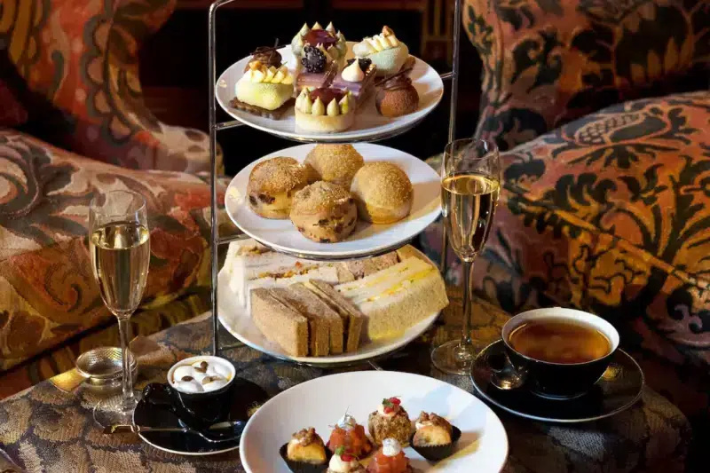Elegant afternoon tea display with pastries, sandwiches, and champagne, set on a decorative table in Prestonfield House.
