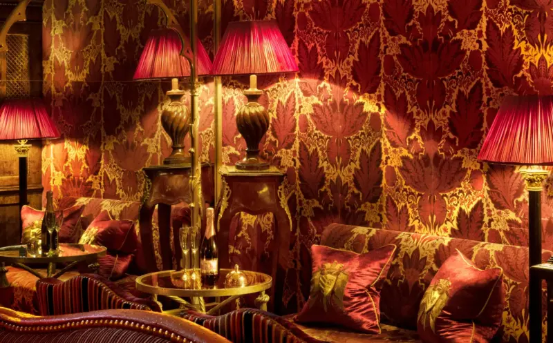 Luxurious interior of Prestonfield House featuring rich red wallpaper, ornate lamps, and plush seating with decorative cus...