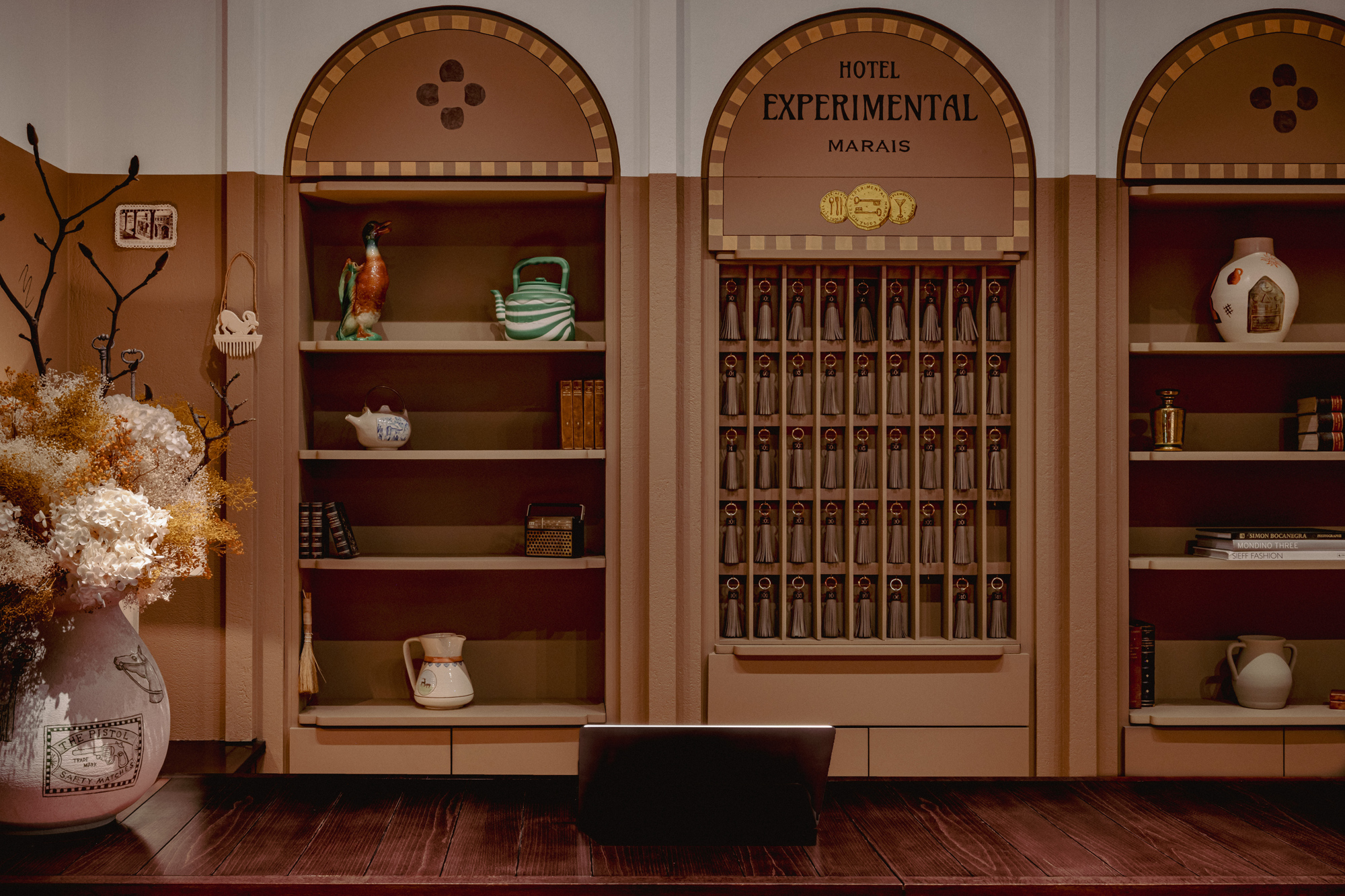 Decorative hotel lobby shelf with vintage items and a floral arrangement, titled "Experimental Marais.