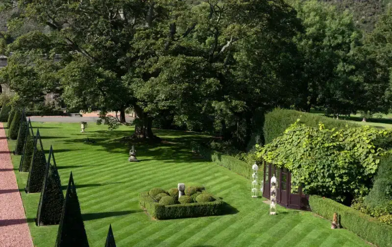 Lush green garden at Prestonfield House featuring neatly trimmed hedges, sculptures, and a gazebo.