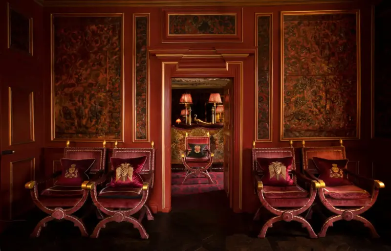 Luxurious leather room with ornate floral wallpaper, plush seating, and warm lighting, showcasing elegant interior design.