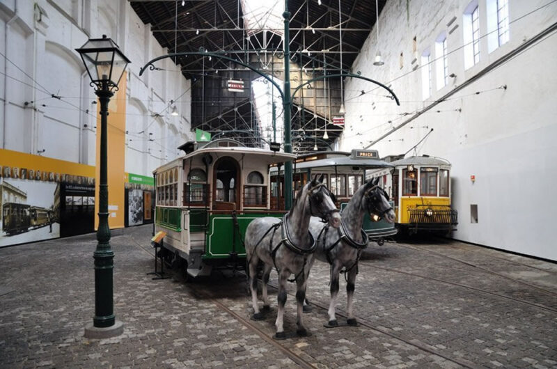Historic tram museum interior featuring a horse-drawn tram and electric trams in Porto.