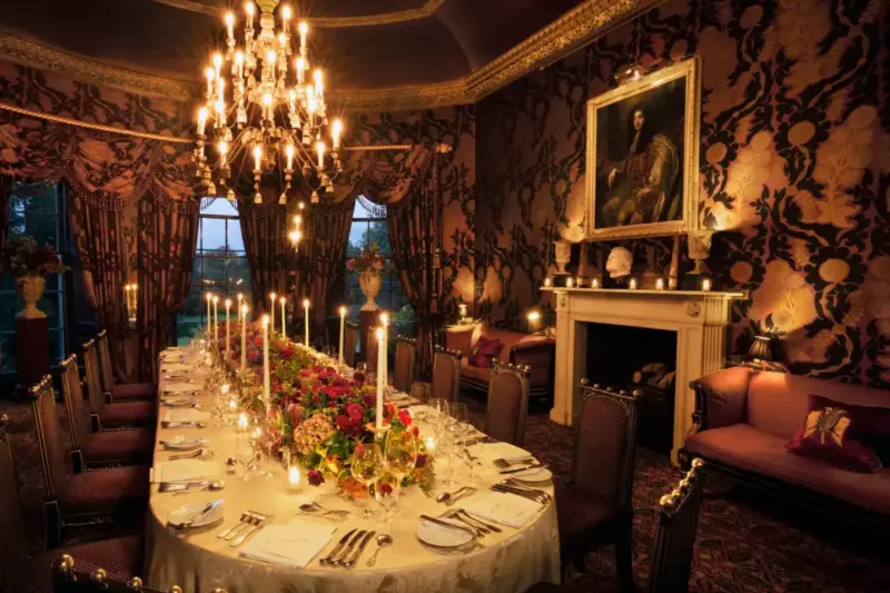 Elegant dining room at Prestonfield House, featuring a long table adorned with flowers and candles, under a chandelier.