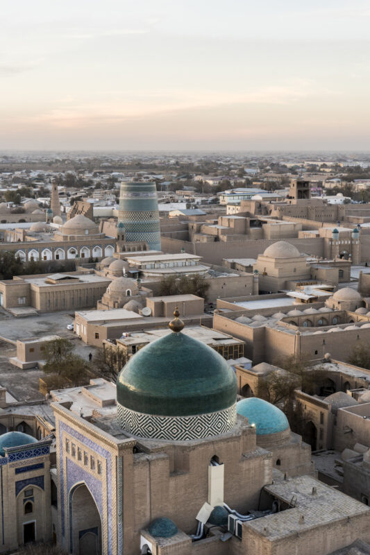 Panoramic view of ancient buildings with domes and minarets in Uzbekistan at sunset.