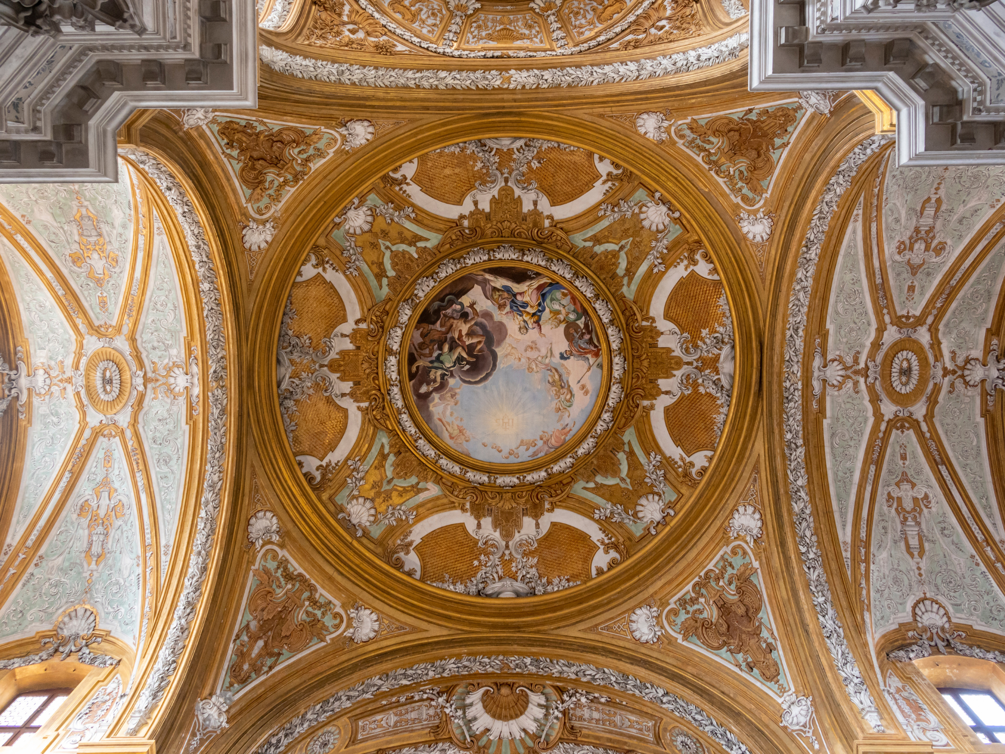 Ornate ceiling with intricate frescoes and gilded details, featuring a central circular painting in a Venetian interior.