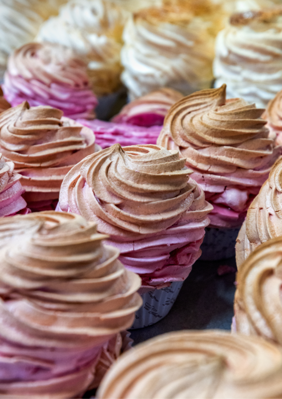 Colorful cupcakes with swirled pink and brown frosting arranged closely together.