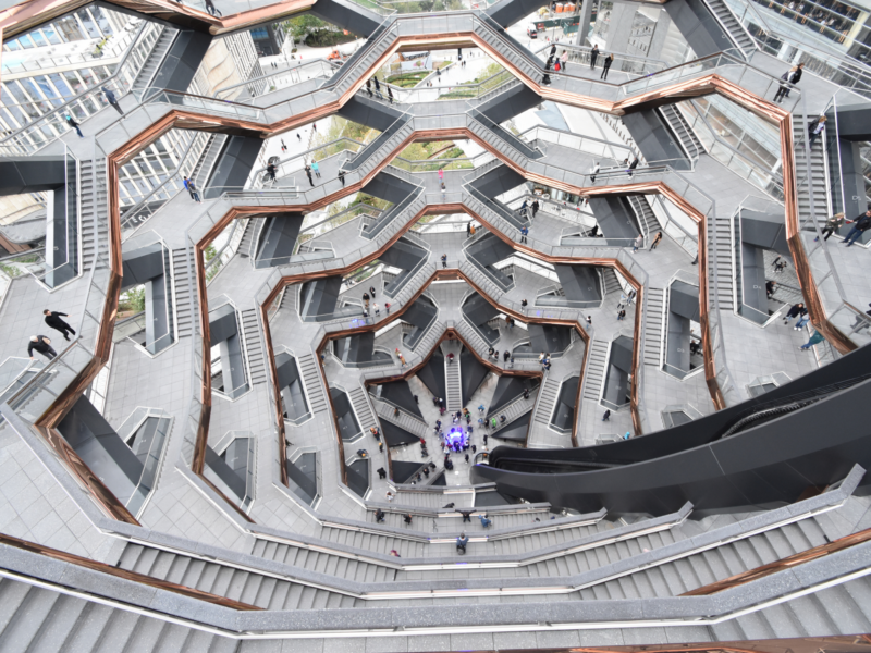 Aerial view of a modern, honeycomb-shaped staircase with multiple levels and people walking on the stairs.