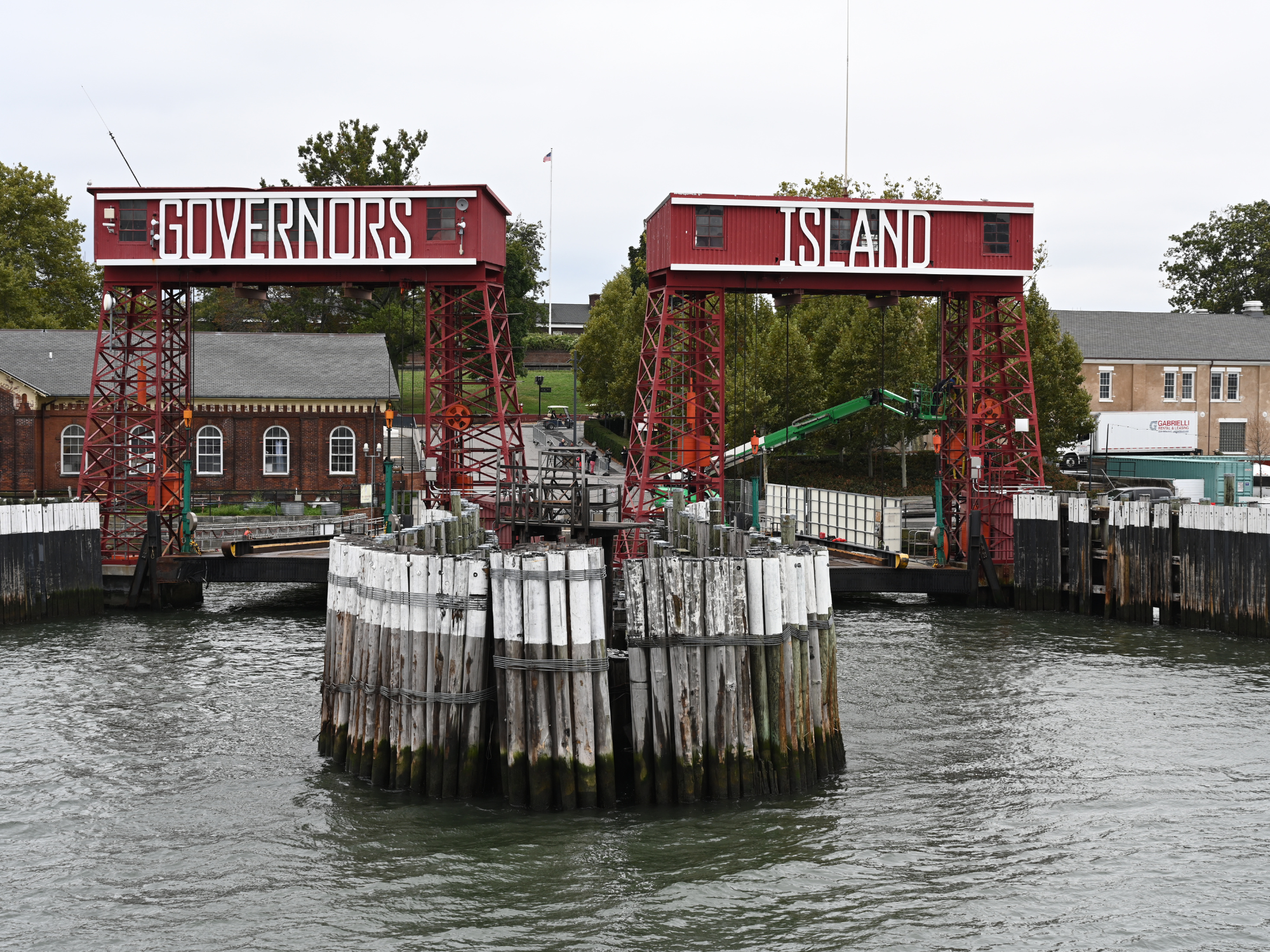 Red steel structures labeled "GOVERNORS" and "ISLAND" at a waterfront dock, with wooden pilings in the foreground.